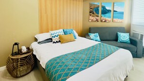 Un dormitorio con cama, sofá, televisión montada en la pared y ventilador de techo.