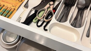 Un cajón con utensilios de cocina ordenados, incluyendo palillos, un cuchillo, una cuchara y un par de tijeras.