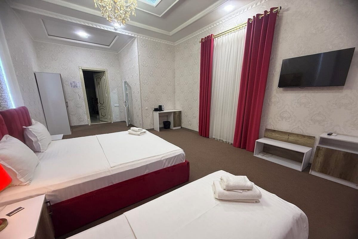 A hotel room with two beds, a TV, a desk, and a bathroom.