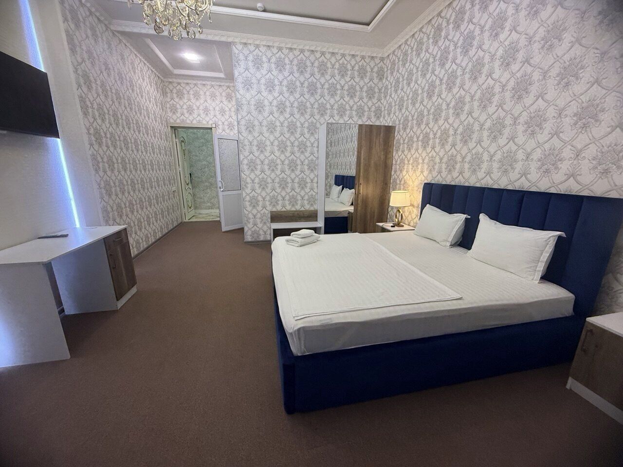 Une chambre d’hôtel moderne avec un grand lit, des tables de chevet, un bureau et un miroir.