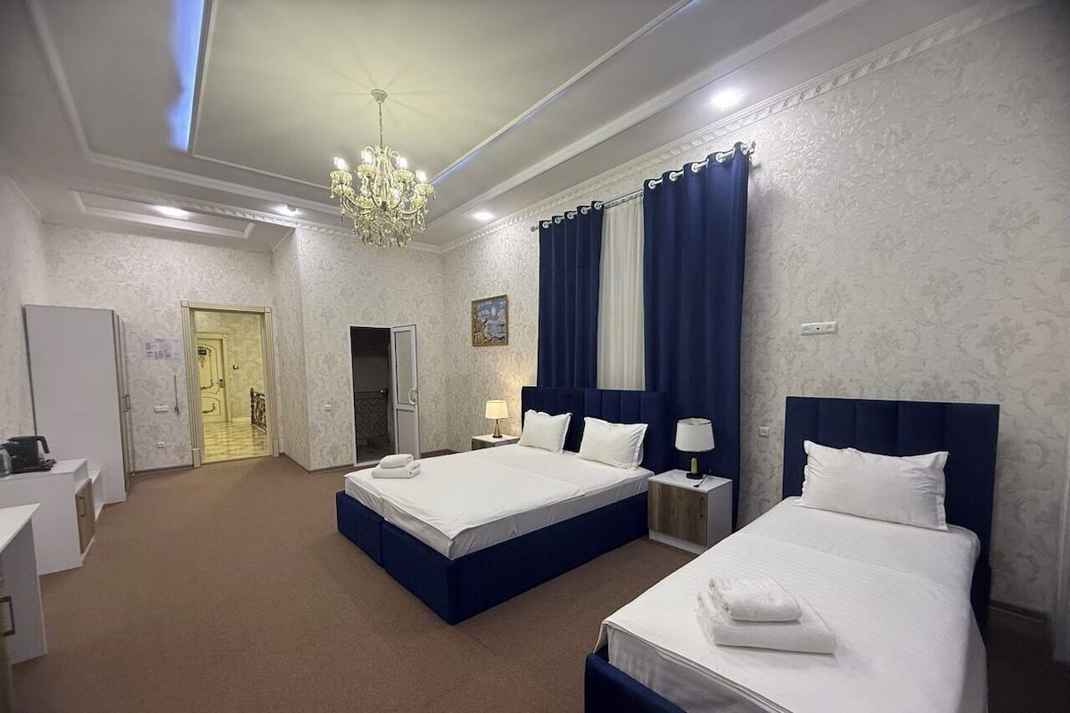 A hotel room with two beds, a chandelier, a bathroom, and a desk.
