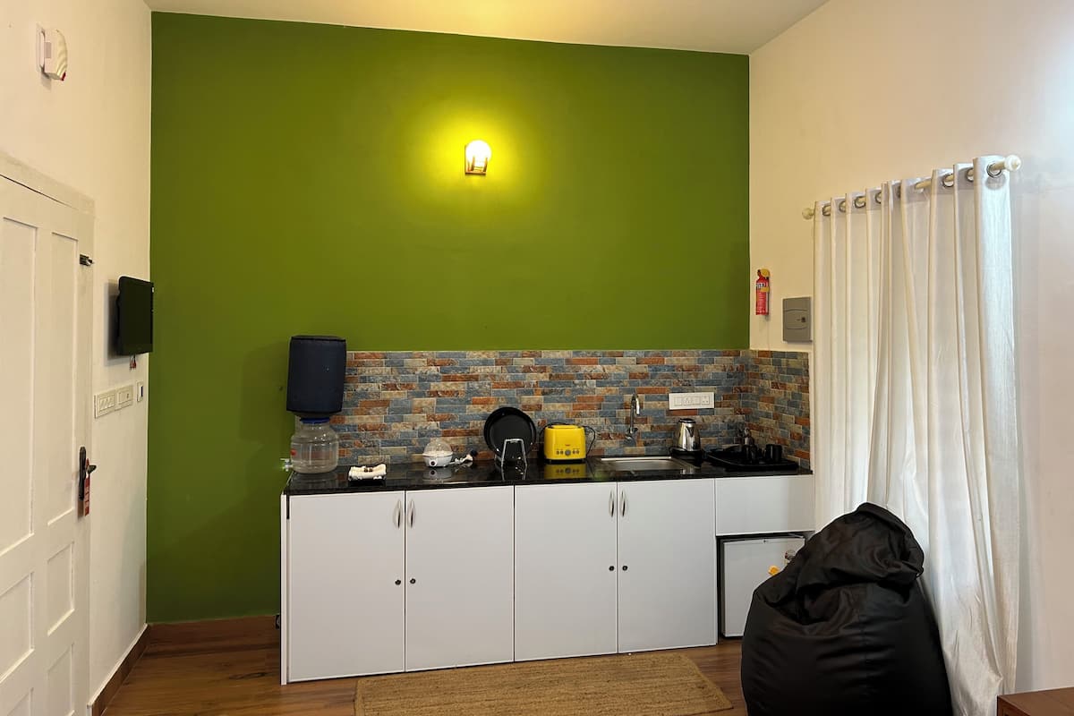 A compact kitchen with a green accent wall, a built-in stove, and a small refrigerator.