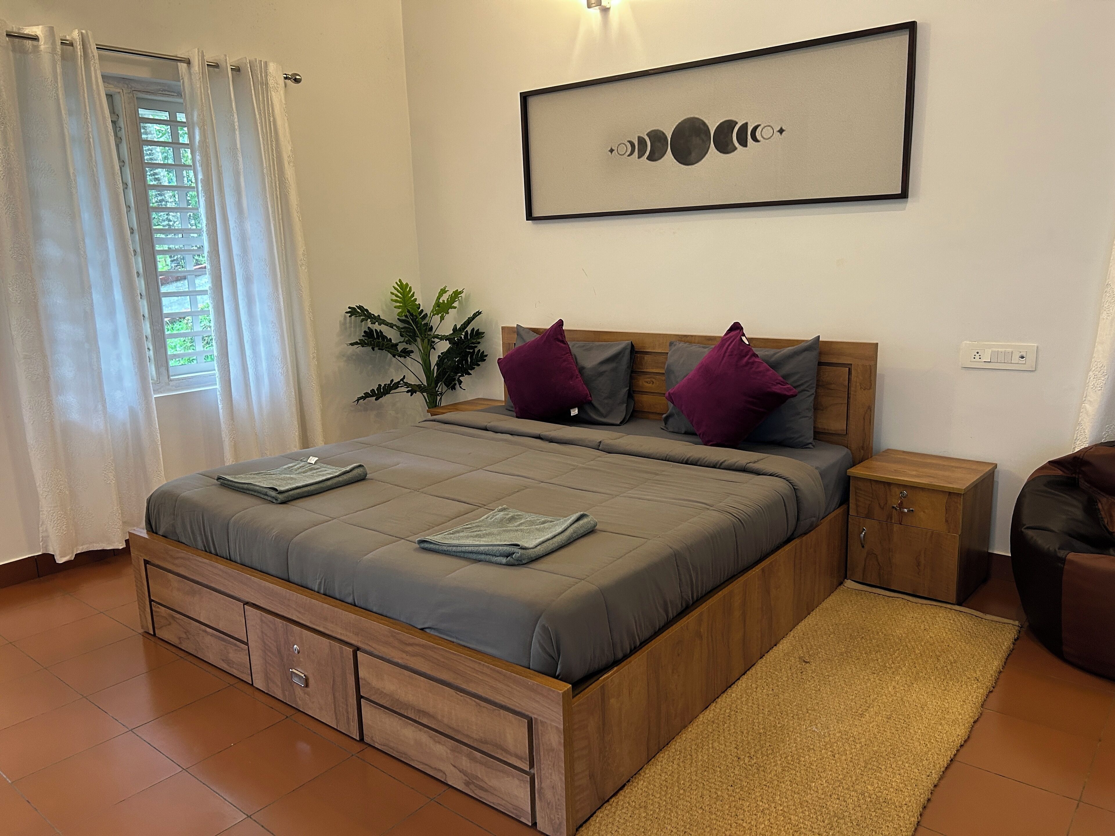 Un dormitorio con una cama, mesitas de noche de madera, una planta pequeña y un cuadro colgado en la pared.
