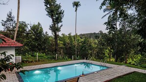 A rectangular swimming pool with a tiled deck, a bench, and a ladder. - Exuberance Stays (Sulthan Bathery)