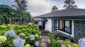 Une maison avec une façade en pierre, un toit en tuiles et un jardin agrémenté d’hortensias.