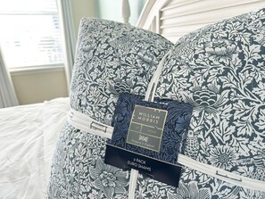 A bed with two pillows featuring a floral pattern, a tag indicating 'William Morris' and 'Euro Shams', and a white headboard. - Margaritaville Luxe Cottage • 2 Master Suites • Disney ~5m • Walk to Fun & Eats (Kissimmee)