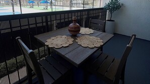 A table with a vase and coasters on a balcony with a view of a sports field. - Newport Beach Modern Studio With A Patio-A/C-Resort Pool- 24/7 Gym- & more (Newport Beach)