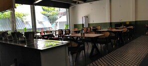 A restaurant with indoor seating, a counter with a menu, and a view of the outside. - MOON LIGHT RESORT (Idappadi)