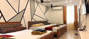 A modern hotel room with two beds, a ceiling fan, an air conditioning unit, and a TV mounted on the wall. - MOON LIGHT RESORT (Idappadi)
