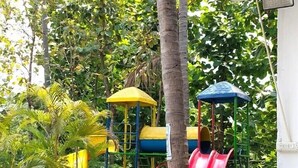 A playground with slides and climbing structures, surrounded by potted plants and trees. - MOON LIGHT RESORT (Idappadi)