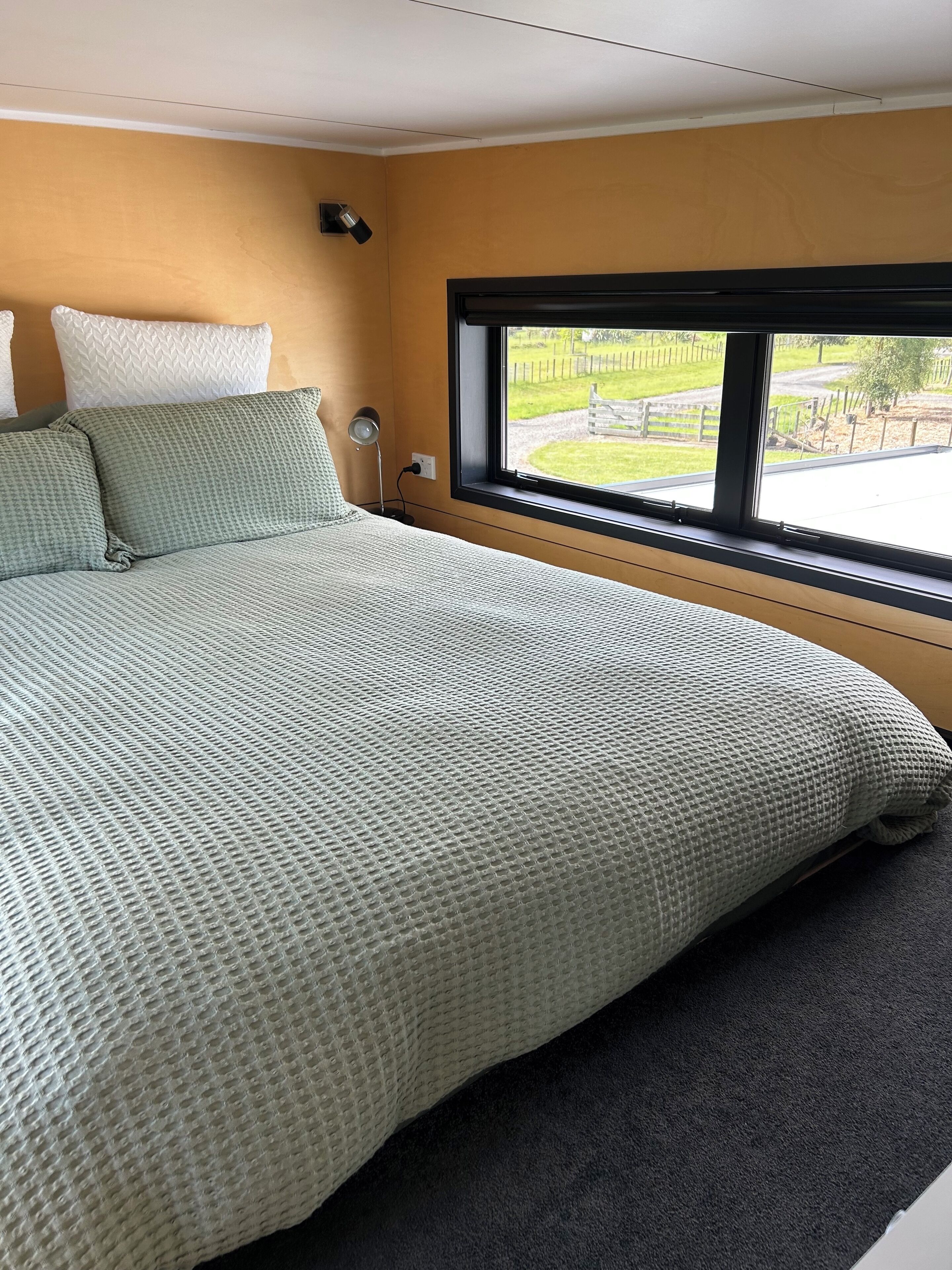Una camera da letto con un letto grande, una finestra che dà su un giardino e una lampada da comodino.