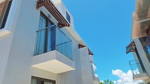 Um edifício moderno com janelas amplas, uma varanda e um céu azul claro.