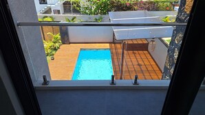 Vista de uma piscina com deck de madeira e guarda-corpo de metal.