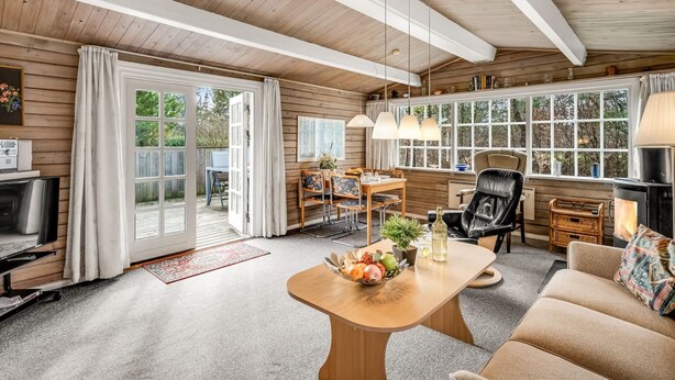 Een knus blokhutinterieur met houten inrichting, een eethoek, een bank en een open haard.