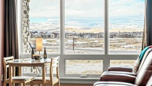 Een kamer met een groot raam met uitzicht op een besneeuwd landschap en een klein stadje.