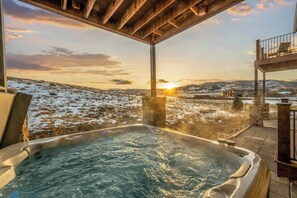 Un bain à remous avec vue sur un paysage enneigé et un coucher de soleil.