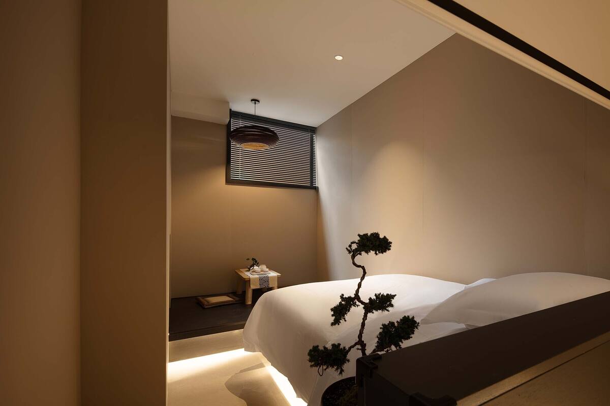 Een moderne slaapkamer met een bed, nachtkastje en een potplant.