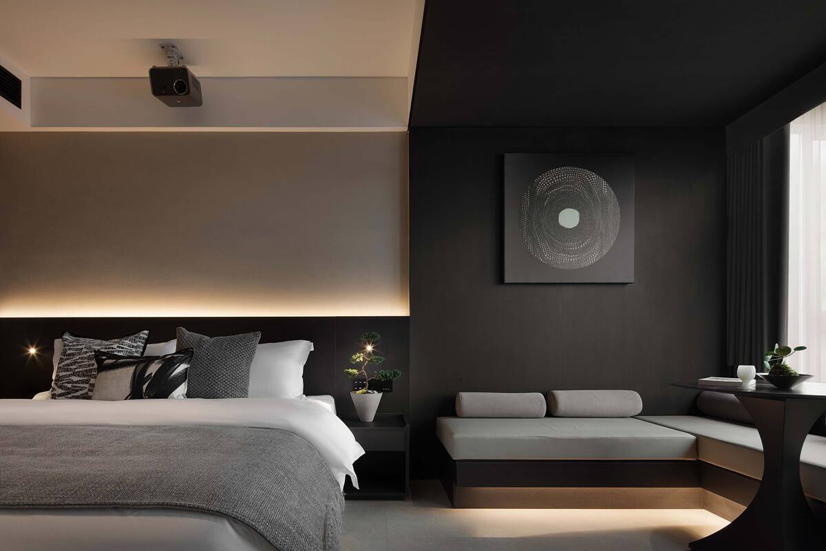 Een moderne slaapkamer met een bed, nachtkastje en een zithoek met een tafeltje.