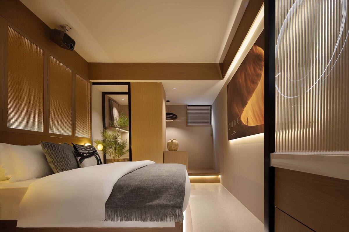 Een moderne slaapkamer met een groot bed, houten lambrisering en uitzicht op de omgeving.