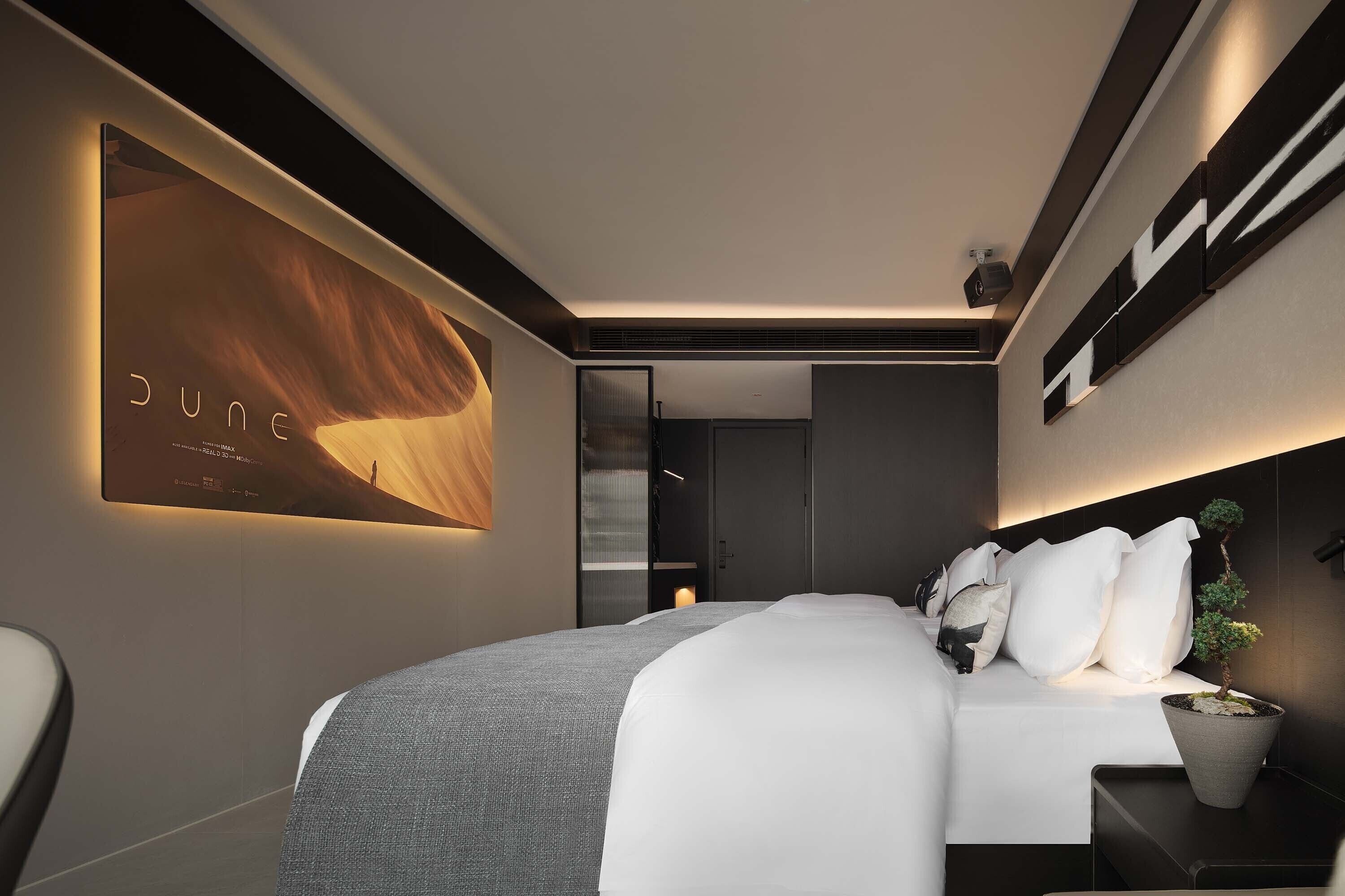 Habitación de hotel moderna con una cama grande, un televisor de pared y una planta en maceta.
