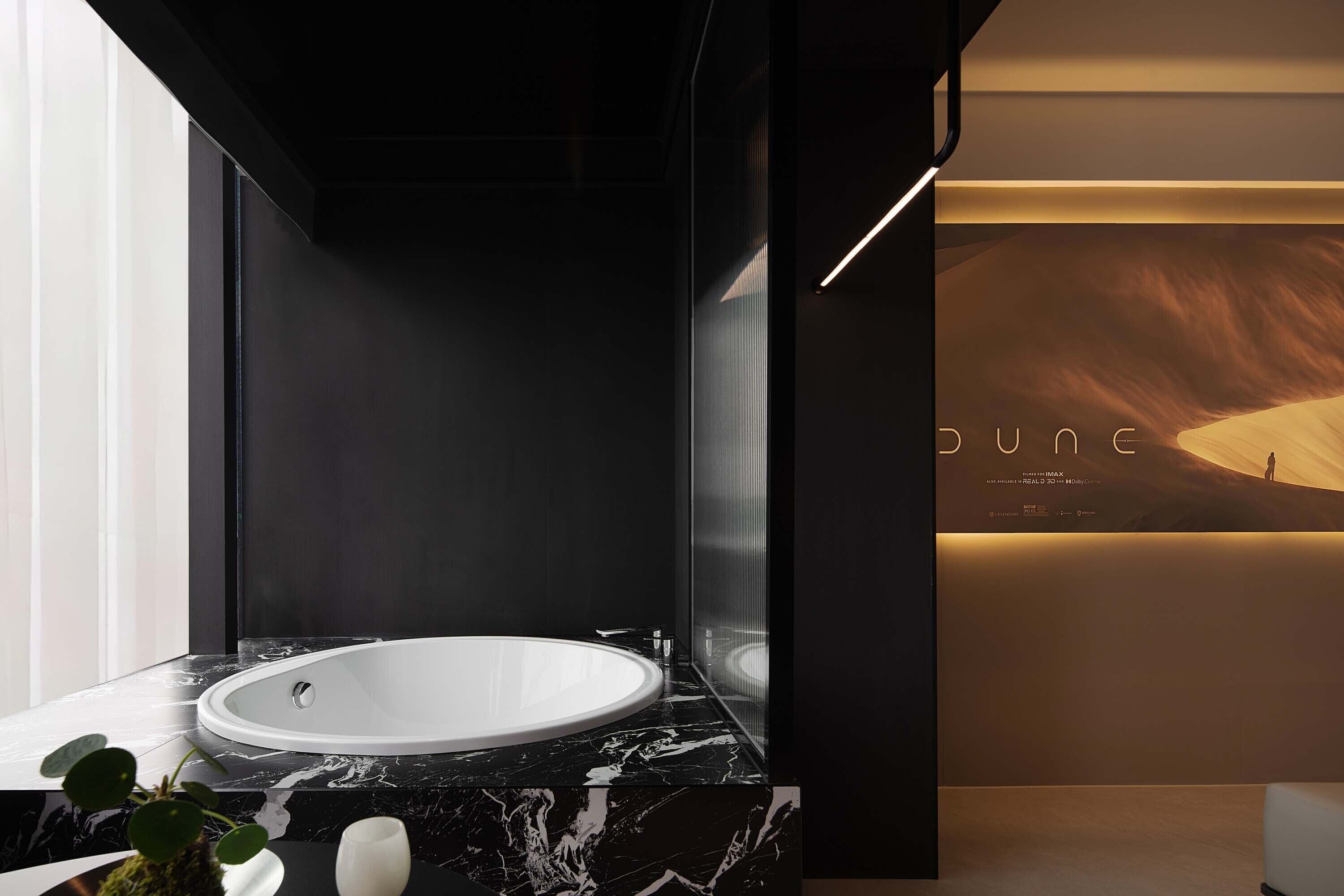 Une salle de bain moderne avec une grande baignoire ovale, un comptoir en marbre et un lavabo fixé au mur.