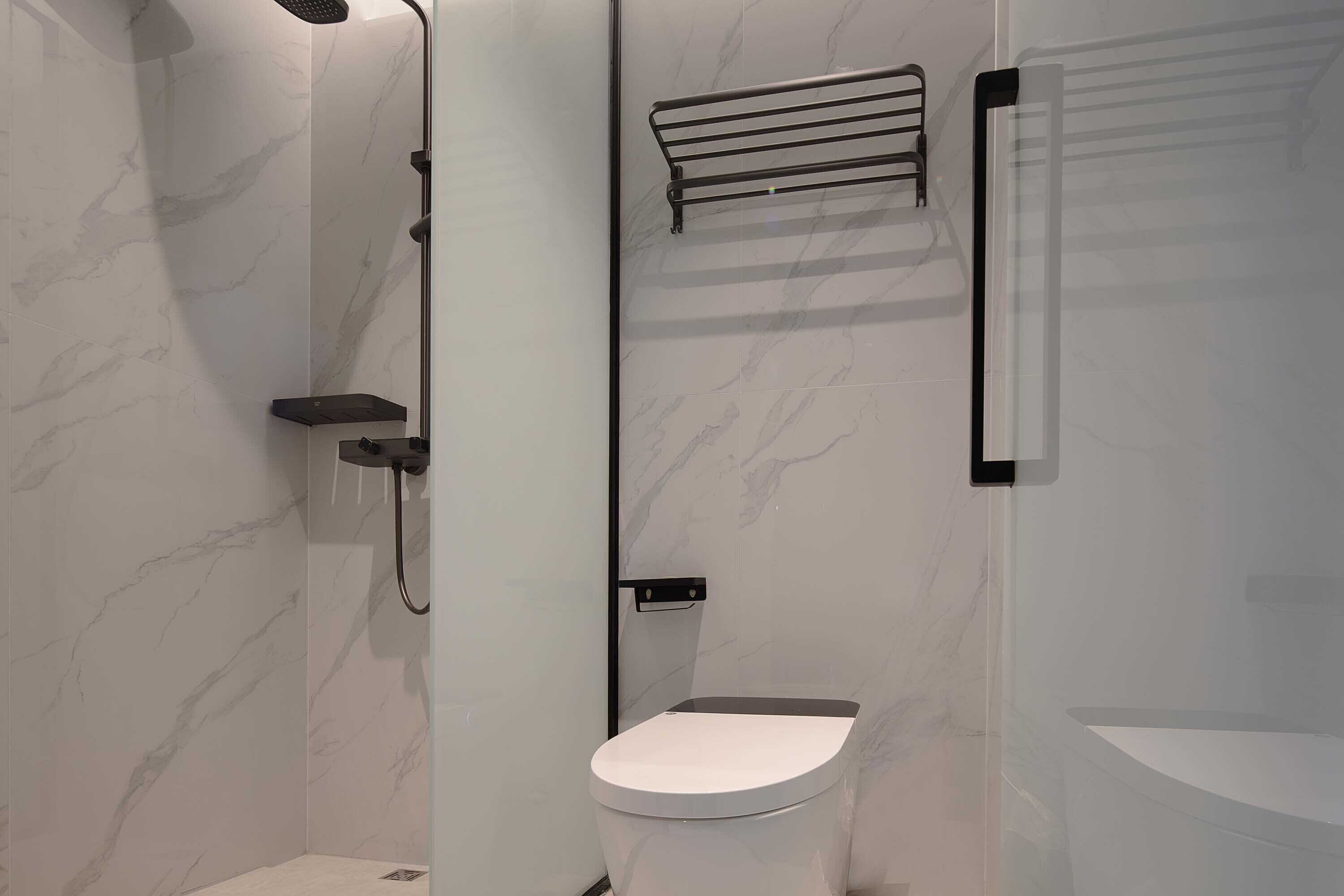 A modern bathroom with a shower, toilet, and a glass-enclosed shower area.