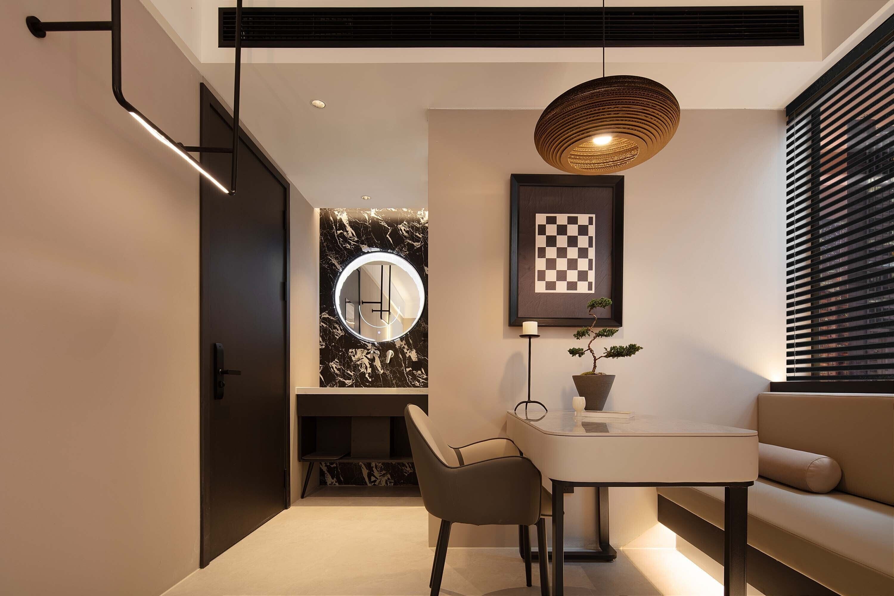 Un interior moderno con zona de comedor, sofá, espejo redondo y tablero de ajedrez enmarcado.