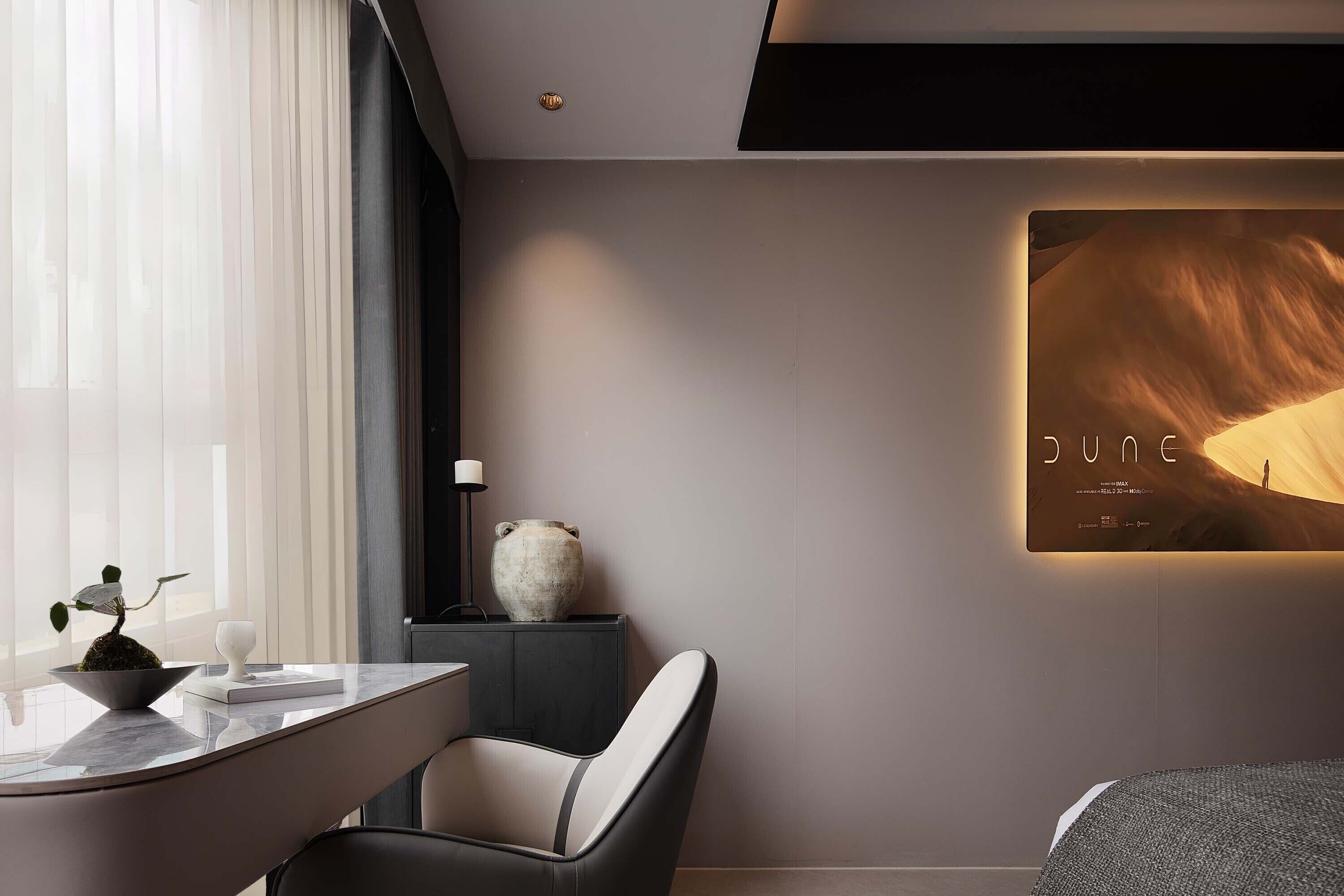 A modern hotel room with a minimalist design, featuring a large window with sheer curtains, a sleek black and white chair, a marble countertop, and a large framed artwork on the wall.