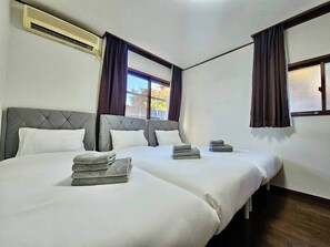 Habitación de hotel con dos camas, ventana con cortinas, aire acondicionado y vista al exterior.