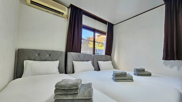 Ein Hotelzimmer mit einem großen Bett, einem Fenster mit Vorhängen und einer Klimaanlage an der Wand.