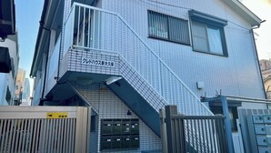 Ein Gebäude mit Kachelfassade, einer sichtbaren Treppe und einem Schild, das einen Parkplatz kennzeichnet.