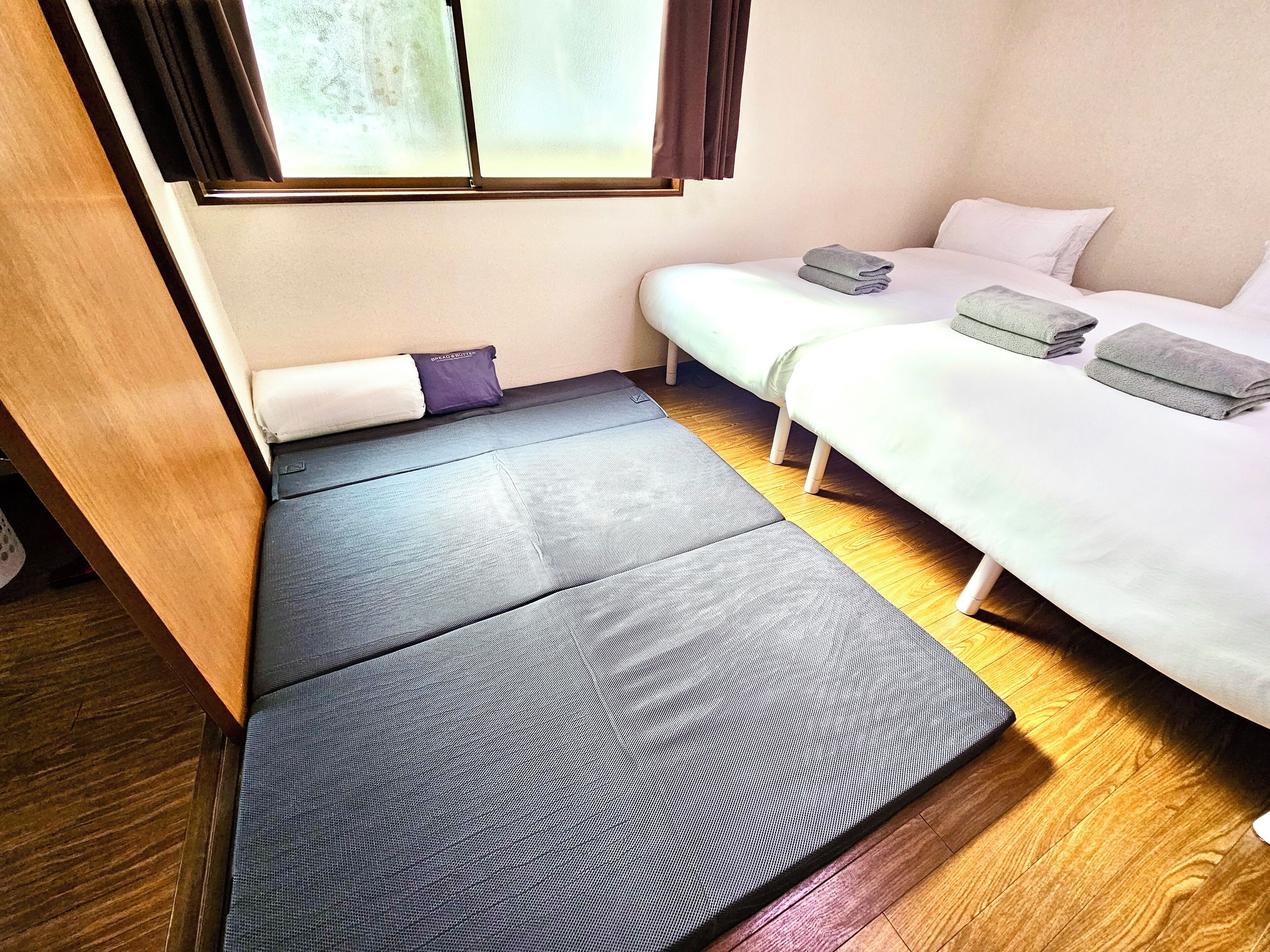 A compact room with a bed, a small seating area, and a window with curtains.