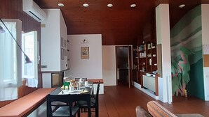 A dining area with a wooden bench, a table set with plates, cups, and a green basket. - Cozy attic in quiet area near road junctions and commercial area (Via Pontebbana)