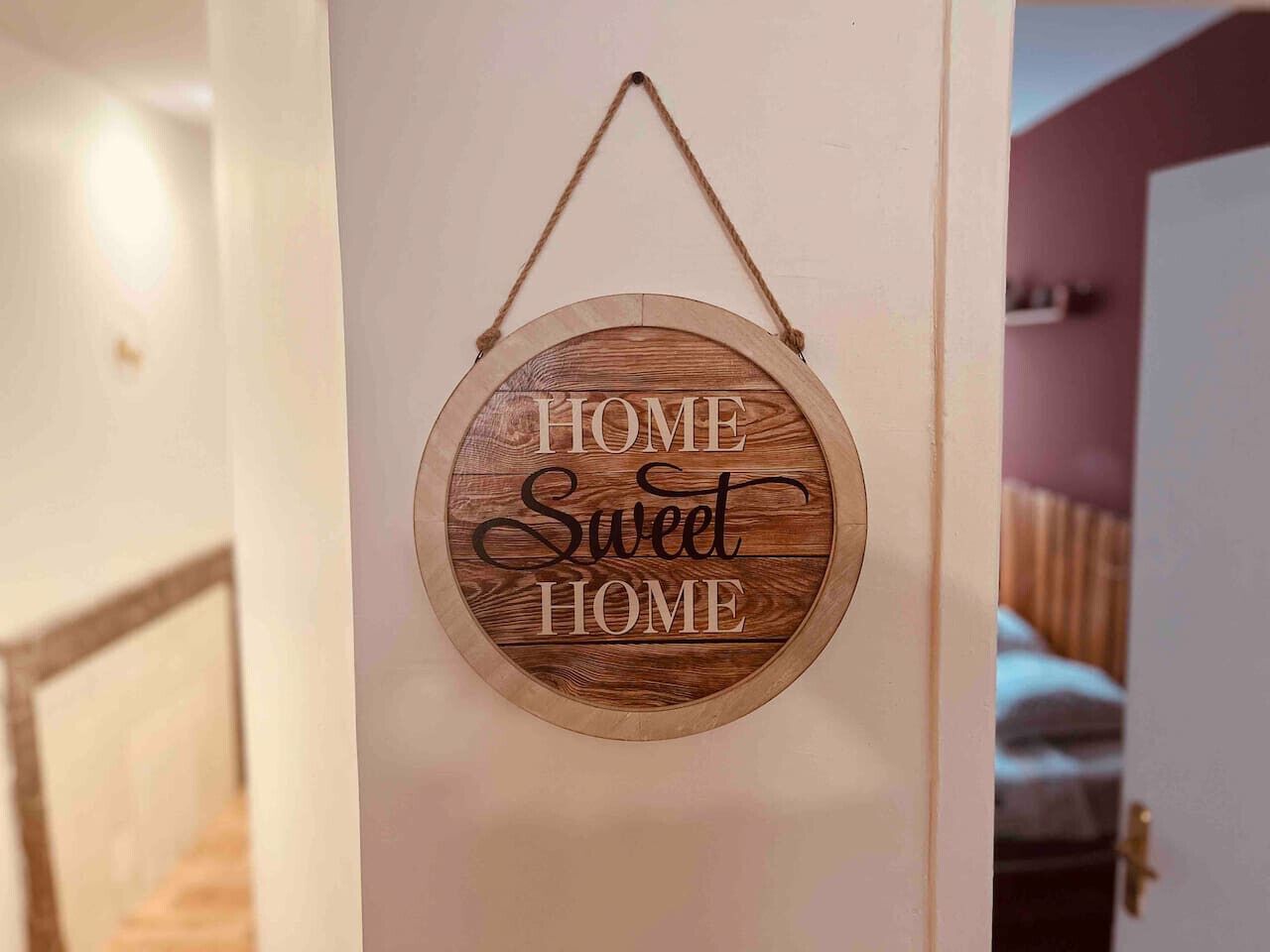 A circular wooden sign with the words "HOME Sweet HOME" hanging on a door.