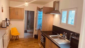 A compact kitchen with wooden cabinets, a black countertop, and a single sink. - Le Ch`ti Cambrai, Logement Élégant, Centre ville (Cambrai)