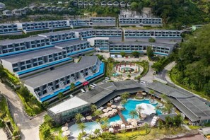Un complexe hôtelier comprenant plusieurs bâtiments, une piscine centrale et des espaces verts environnants.