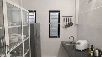 A compact kitchen with white cabinets, a refrigerator, a window, and a countertop with a sink and a toaster.
