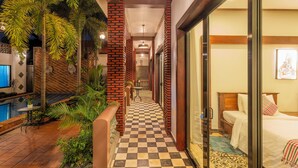 A hotel corridor with checkered flooring, a pool area, and a bed with a view. - 6 Rooms Oudom Sokhomal Private Wellness Villa & Retreat (Siem Reap)
