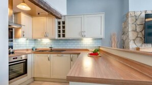 Eine moderne Küche mit weißen Schränken, einer Holz Arbeitsplatte und einer Wand mit Steinverkleidung.