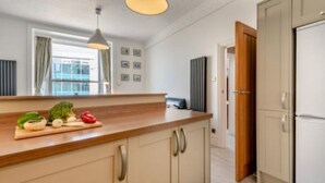 Eine moderne Küche mit einer Holzarbeitsplatte, einer Hängelampe und einem Kühlschrank.