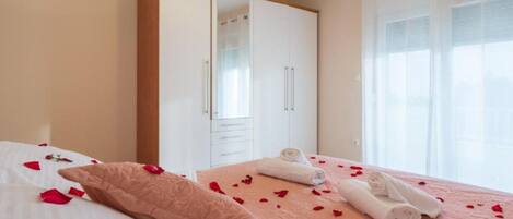 A hotel room with a bed, a wardrobe, and a window with sheer curtains.