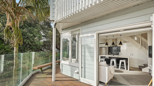 Et moderne hus med terrasse, et køkken og en trappe.