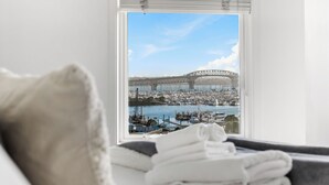 Et værelse med stort vindue, udsigt over lystbådehavn og bro.
