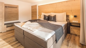 Ein modernes Schlafzimmer mit einem großen Bett, einem Holzkopfteil, Nachttischen und einem Kleiderschrank.