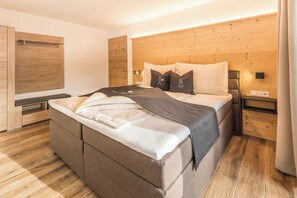 A modern bedroom with a large bed, wooden headboard, bedside tables, and a wardrobe. - XL Apartment 2R (Sand in Taufers)