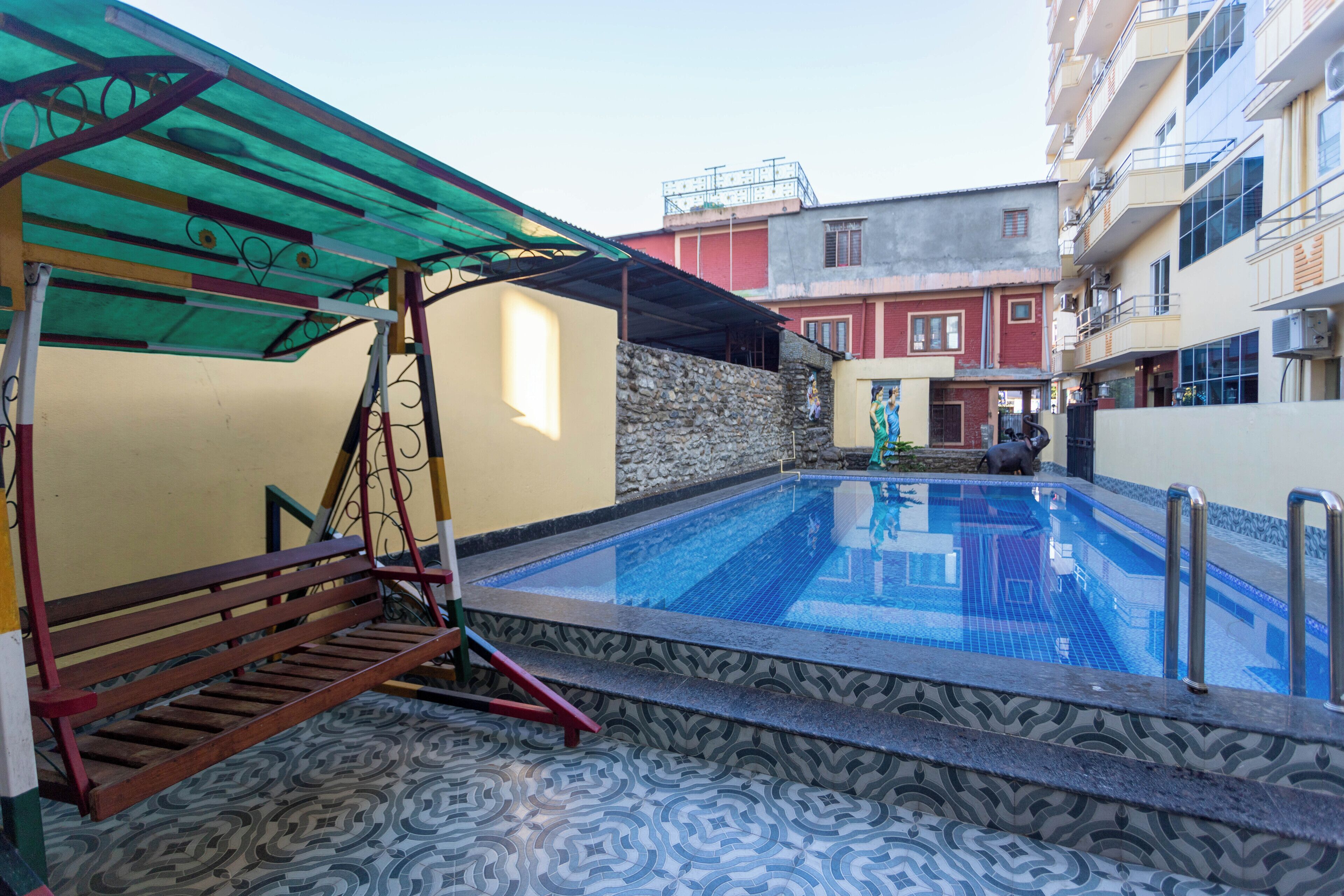 Piscina com borda azulejada, um banco de madeira e uma parede de pedra.