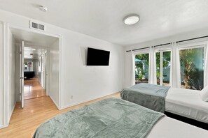 Hotelkamer met een houten vloer, een flatscreen televisie aan de muur en een raam met uitzicht op bomen.