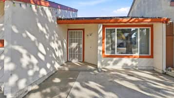A building with a white exterior and orange trim, featuring a door with a metal gate and a window with a view of the outside.