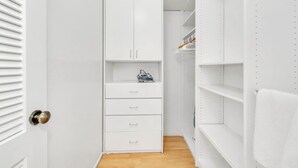 Un placard blanc, dont les portes sont ouvertes, laissant apparaître des étagères et des tiroirs.