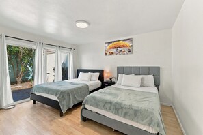 Une chambre avec deux lits, une table de chevet, une lampe et un tableau au mur.